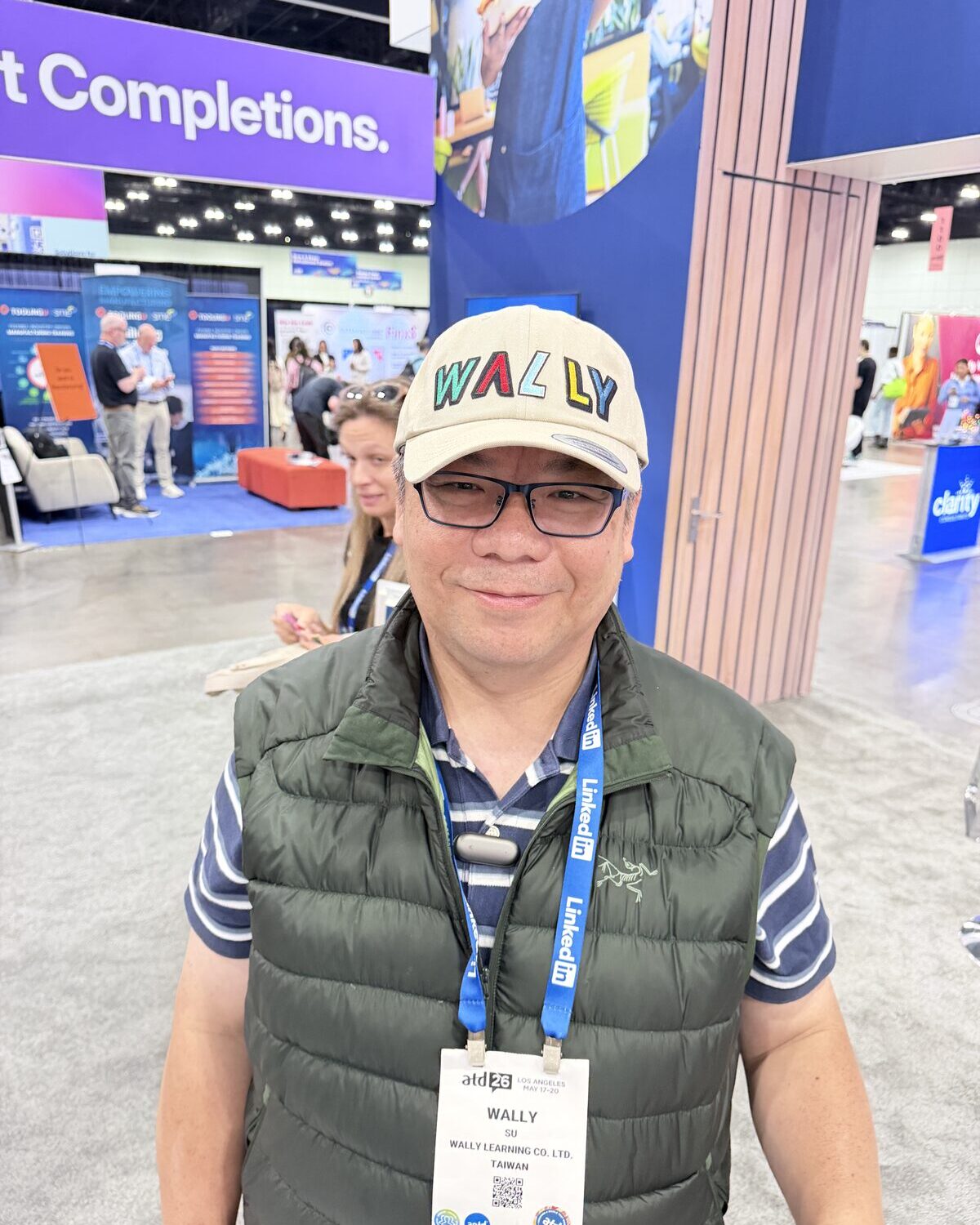 A conference guest wearing a custom-embroidered cap reading WALLY