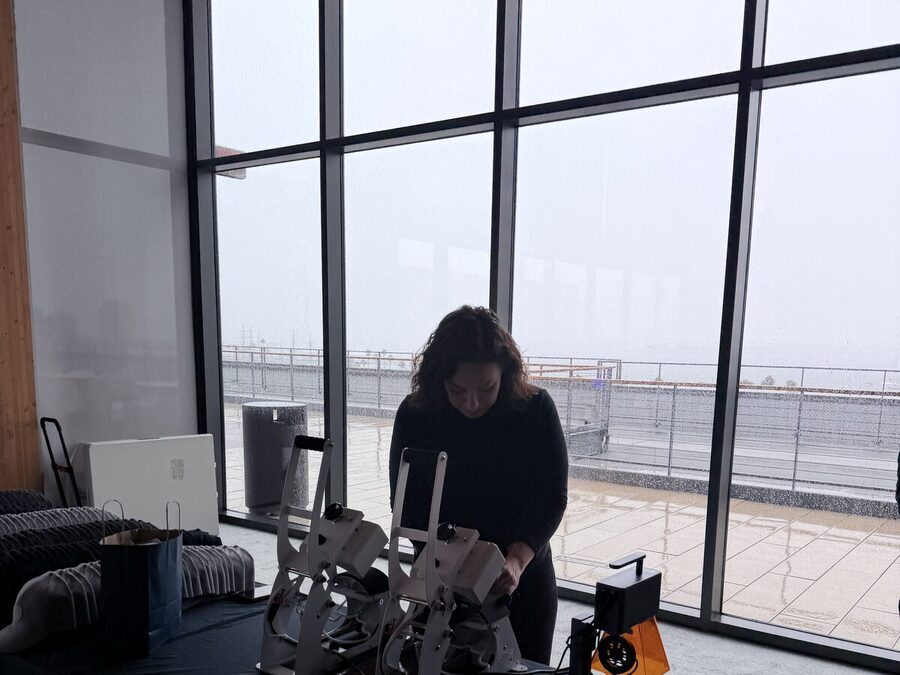 An operator working twin white heat-press stations beside racks of garments